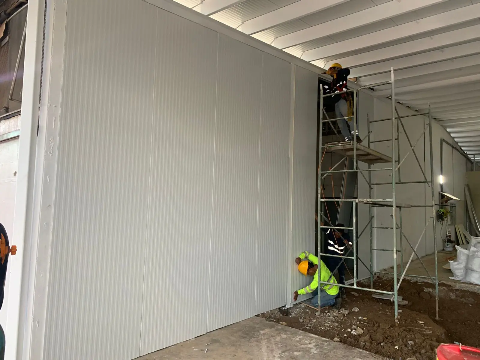 Técnicos instalando pared de panel sándwich Europanel en proyecto comercial de Panamá, con refuerzo estructural y sellado poliuretano.